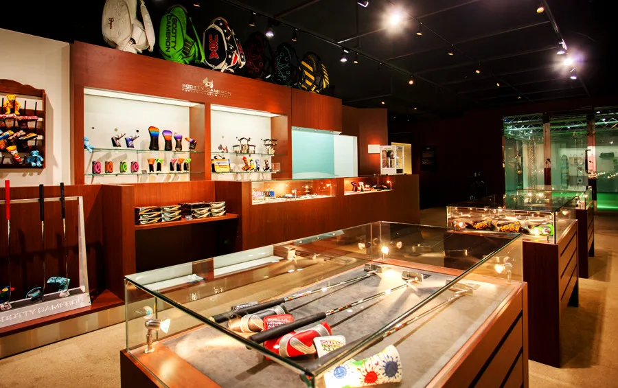 A golf shop interior displaying various golf equipment, including clubs and accessories, in glass cases and shelves.