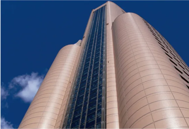 A tall, modern high-rise building with rounded architecture against a clear blue sky.